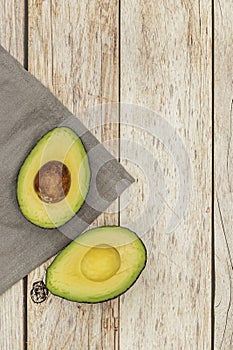 A ripe avocado cut in half on a gray cloth