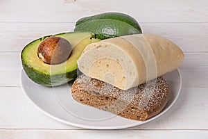 Ripe avocado, white and black bread on a plate. An avocado sandwich can be made with a variety of breads