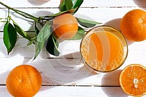 Ripe bio oranges and a glass of fresh squeezed orange juice on white wooden background.Organic Sicilian oranges.Top view