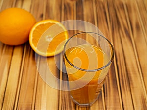 Ripe bio oranges and a glass of fresh squeezed orange juice on wooden background