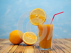 Ripe bio oranges and a glass of fresh squeezed orange juice on wooden background