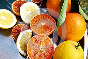 Ripe bio sliced oranges and lemons on steel tray top view. Organic Sicilian oranges. Healthy eating concept. Vitamin C