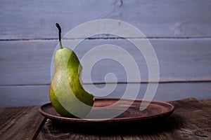 A bite pear on a plate on wooden background
