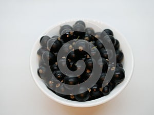 Ripe black currant berries in a small white Cup on a white background. Black currant harvest. Natural vitamin. Healthy food. veget