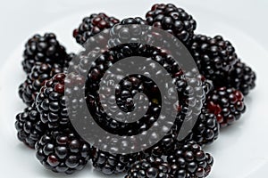 Ripe blackberries on a white plate. Useful forest fruits. Super food