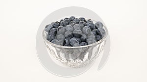 Ripe blueberries in a glass bowl on white background.