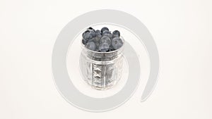 Ripe blueberries in glass cup on a white background