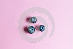 Ripe blueberry berries on a pink background, top view, flat lay