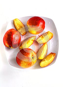 Ripe bright nectarines on a white saucer