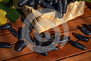 Ripe bunch of black grapes lady`s fingers in a wicker basket with grape leaves on a brown background. Close-up