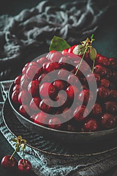 Ripe cherries in a black bowl on black background