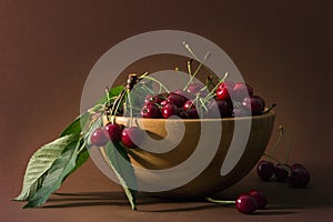 Ripe cherries with leaves in wooden bowl