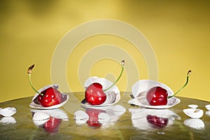 Ripe cherries in plates of white oyster shells on a yellow background