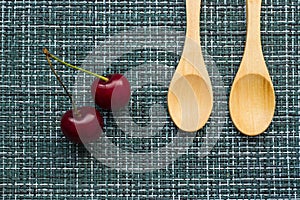 Ripe cherries on a wicker background and two wooden spoons, close-up