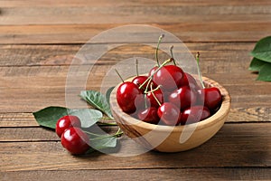 Ripe cherries in a wooden bowl on a wooden table