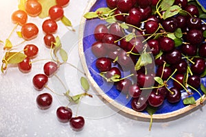 Ripe cherry in a blue plate on a light background