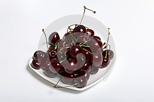 Ripe cherry lies on a saucer. On a white background.