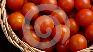 Ripe cherry tomatoes on the kitchen table in a rattan bowl close up.