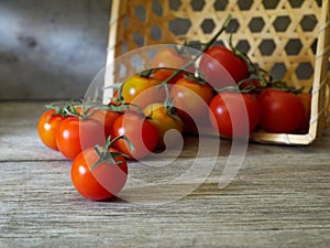 Ripe cherry tomatoes in overturned basket on wooden table