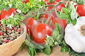 Ripe cherry tomatoes, peppercorns, garlic, basil, on a wooden table