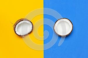 Ripe coconut on yellow and blue colored background, minimal flat lay style top view with copy space. Pop art design, creative