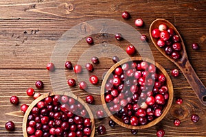 Ripe cranberry in wooden bowl on rustic table from above