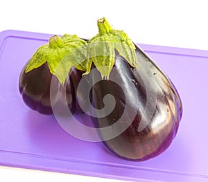 A ripe eggplant on a plastic cutting board