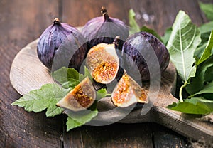 Ripe fig fruits with fig leaves on the wooden background