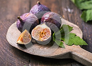 Ripe fig fruits with fig leaves on the wooden background