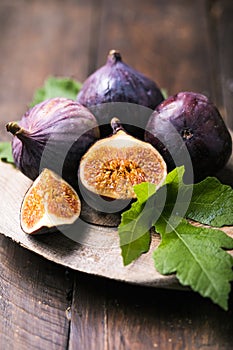 Ripe fig fruits with fig leaves on the wooden background