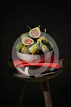 Ripe figs heap on book and old wooden stool