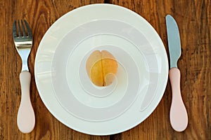 Ripe fresh apricot fruits on a white plate on the wooden background. Copy space, delisious healthy food