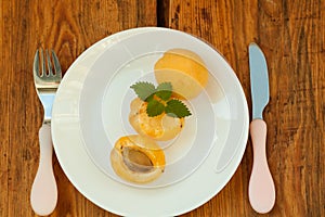 Ripe fresh apricot fruits on a white plate on the wooden background. Copy space, delisious healthy food