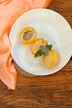 Ripe fresh apricot fruits on a white plate on the wooden background. Copy space, delisious healthy food