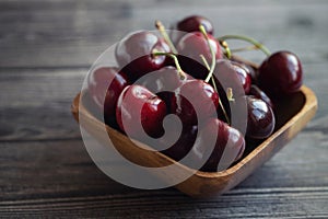 Ripe fresh cherries in a wooden bowl. Food background. Red juicy cherry berry on grey wooden background. Cherries in a