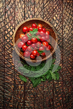 Ripe fresh cherry tomatoes in wooden bowl. Top view, flat lay