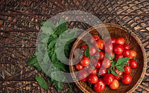 Ripe fresh cherry tomatoes in wooden bowl. Top view, flat lay