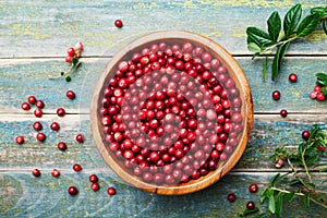 Ripe fresh cowberry lingonberry, partridgeberry, foxberry in wooden bowl on rustic vintage table from above.