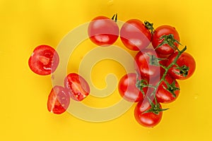 Ripe fresh Juicy organic cherry tomatoes on branch and cut tomato on yellow plastic cutting board. Top view.