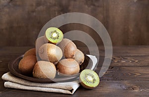 Ripe fresh kiwi fruit in a bowl on a brown wooden background