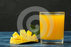 Ripe fresh mango fruit and slices and mango juice in a glass on a blue wooden table. tropical fruit