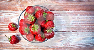 Ripe freshly picked strawberries in bowl on a wooden background. Copy space. Close-up. Top view