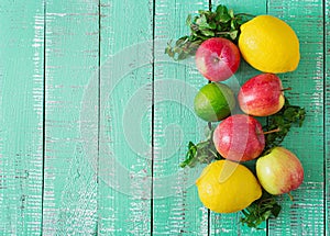Ripe fruits (apples, lemons and limes) on a bright wooden background.