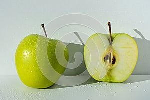 Ripe fruits of a green apple with halves on a white background. Apples with an edged path.