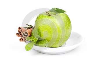 A Ripe Green Apple with mint and cinnamon on plate