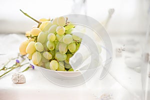 Ripe green brush of grapes in a plate on a windowsill