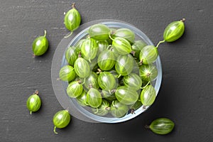 Ripe green gooseberries in a glass transparent bowl and jar on a black  background. Harvest concept agrus. Vegetarian food.Top