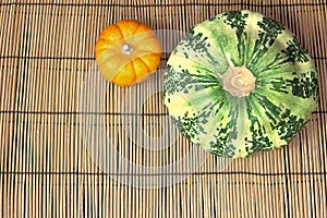 Ripe green patisson, and small pumpkin, lie on a reed mat. View from above. Autumn harvest concept