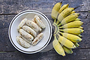 Ripe grilled banana dish and a hand of bananas on black floor