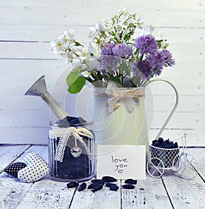 Ripe honeysuckle berry in vintage jar and watering can with wild flowers on the table